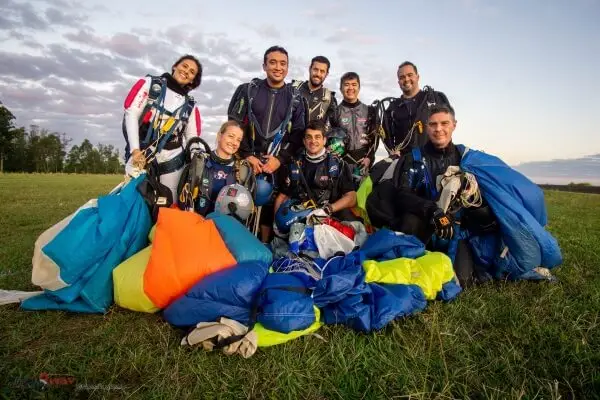Paraquedistas em que acabaram de aterrisar em um campo posando para foto